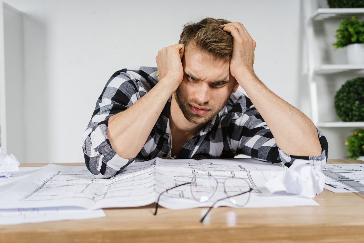 Exhausted,young,adult,architect,freelancer,looking,at,house,project,,sitting