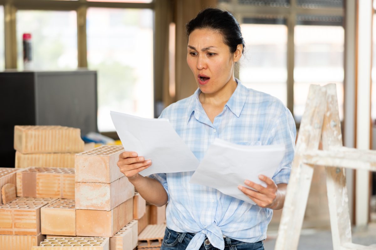 Portrait,of,stressed,woman,owner,of,renovating,house,examining,and