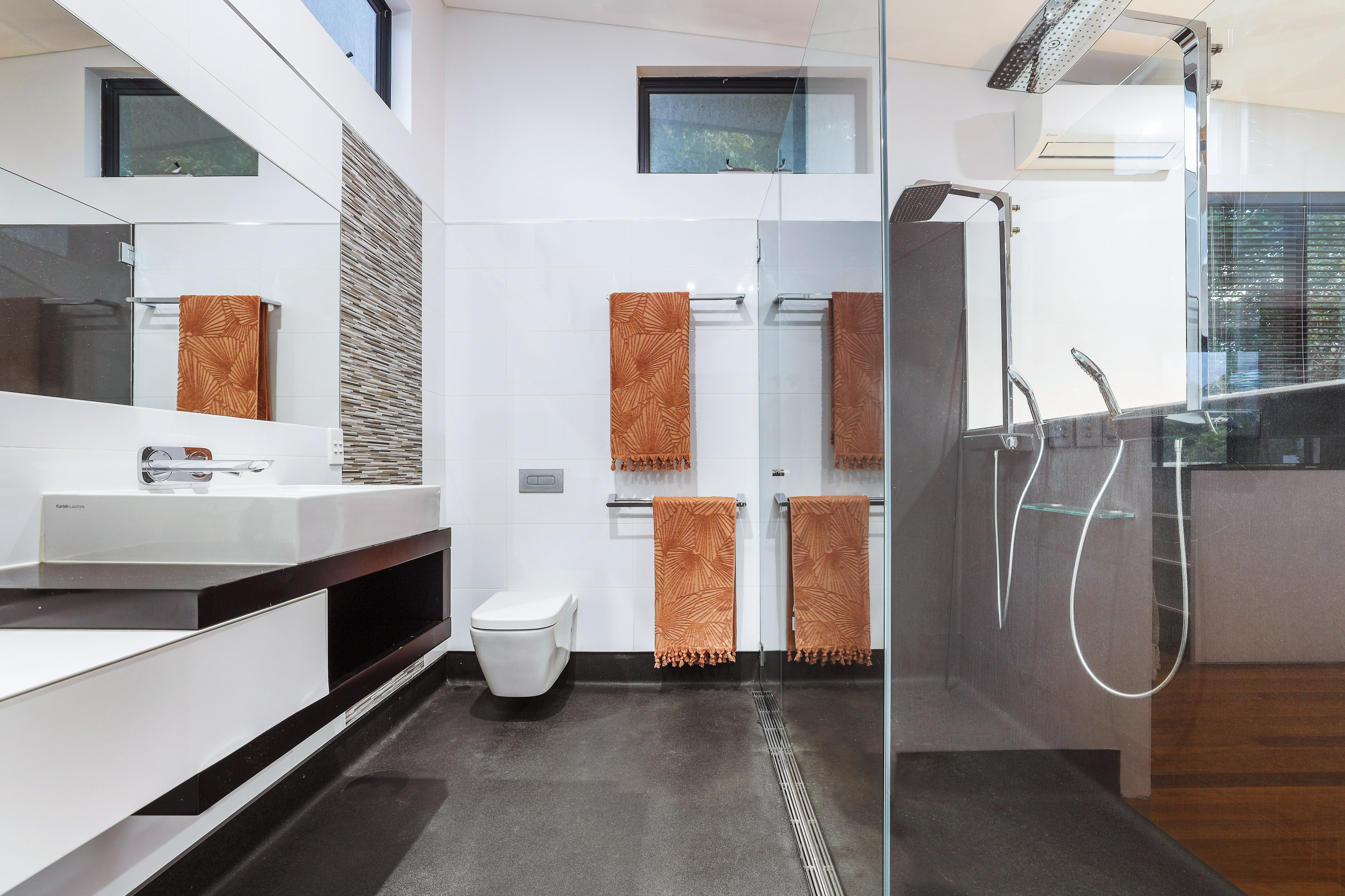 Master ensuite with floating vanity, frameless walk-in shower, large-format grey tiles and mosaic accent at renovated Southport home