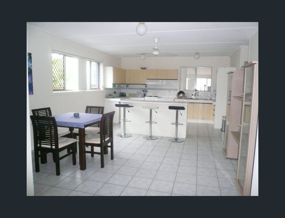 Dated open-plan kitchen with laminate cabinetry, tile floors and security screen windows before Gold Coast renovation