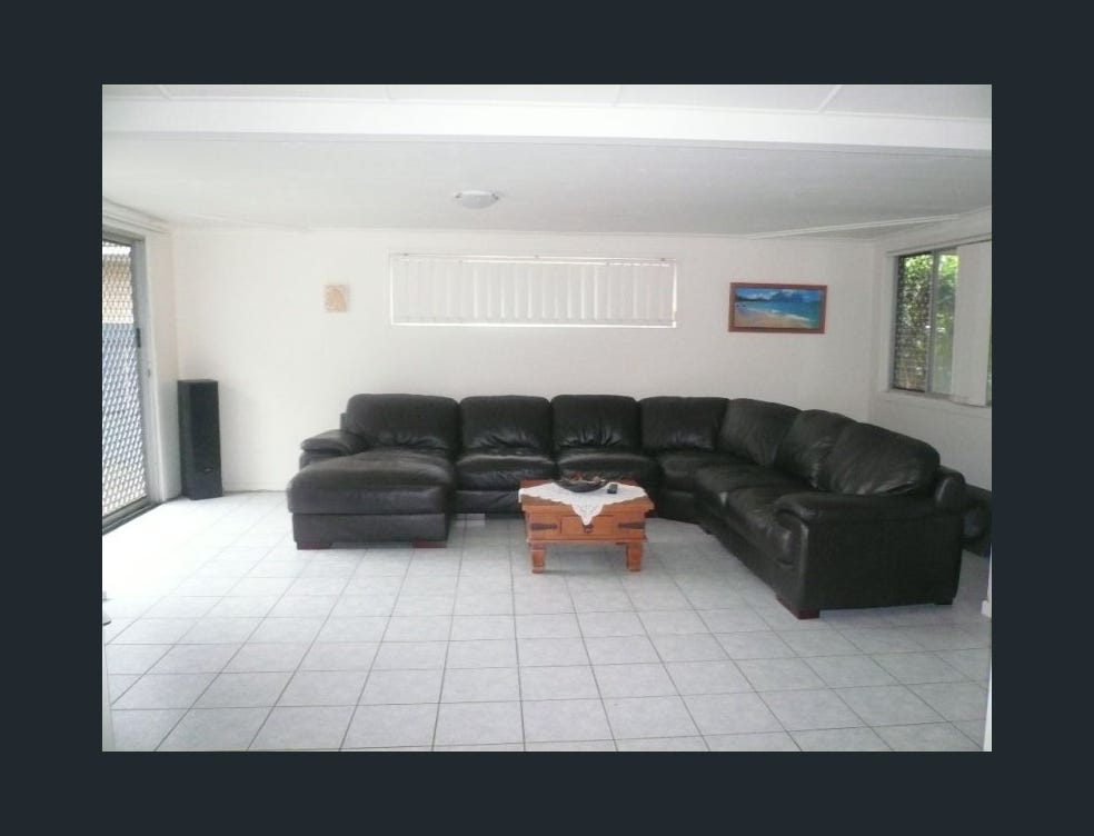 Dated living room with black leather lounge, tile floors and security screen windows before Southport home renovation