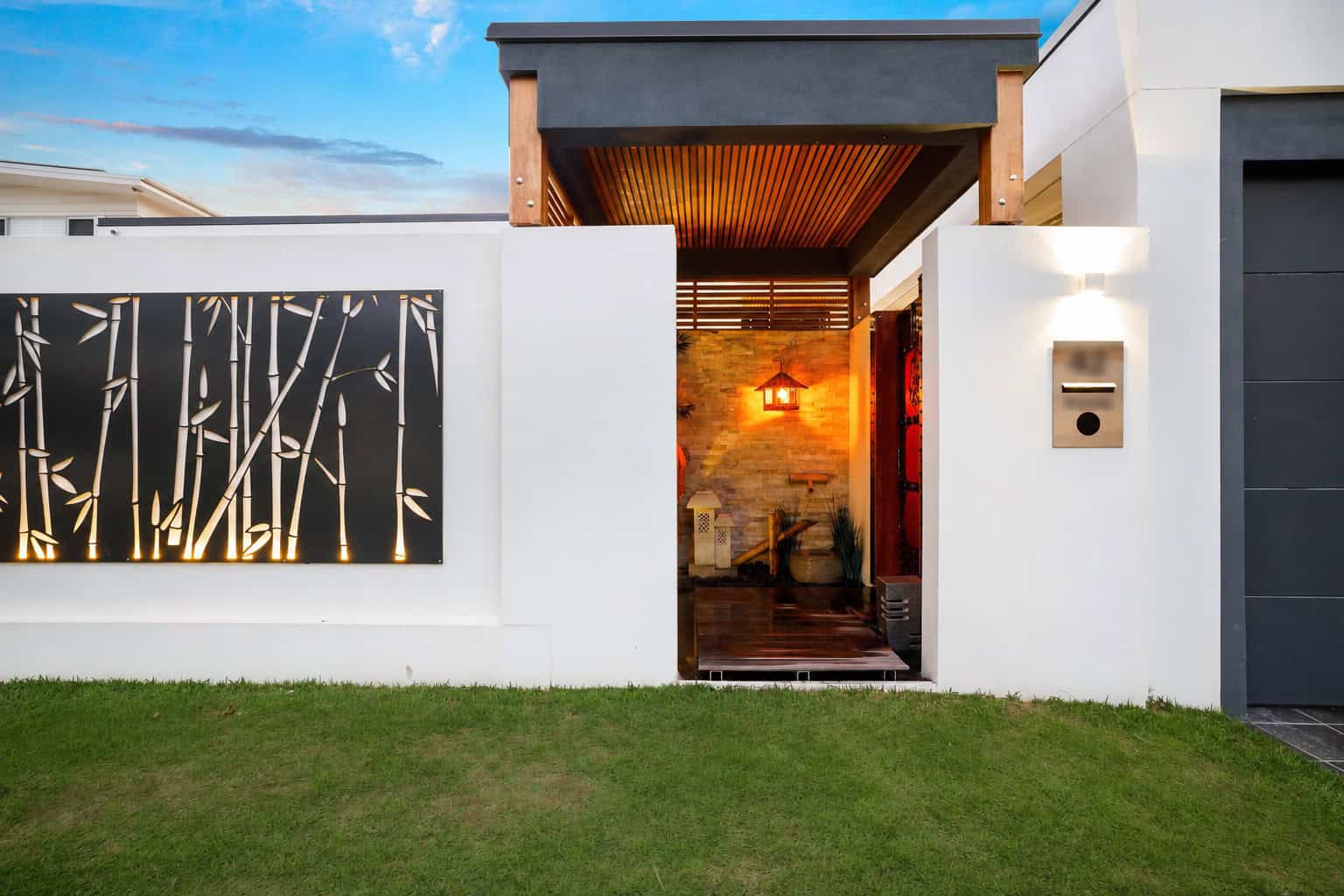 Renovated Gold Coast home entrance with illuminated bamboo screen and private mailbox