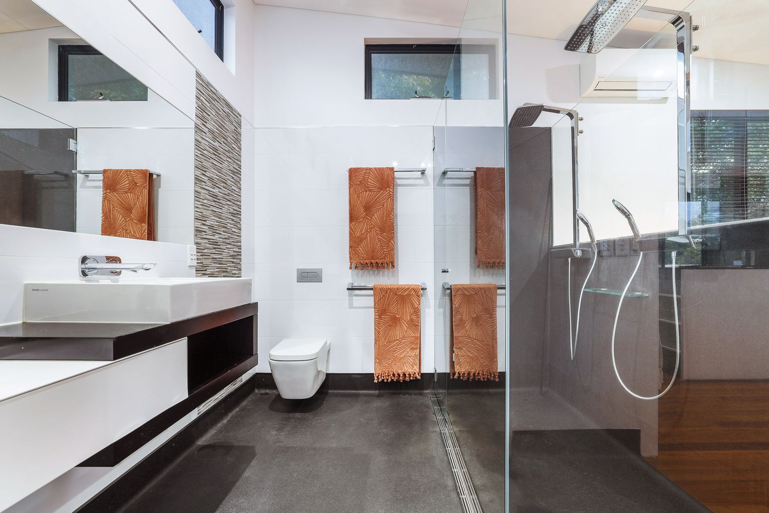 Master ensuite with floating vanity, frameless walk-in shower, large-format grey tiles and mosaic accent at renovated Southport home