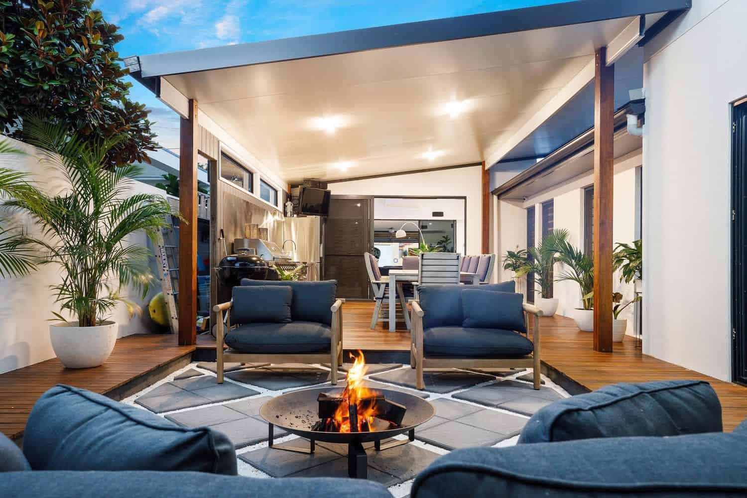 Outdoor fire pit lounge area at twilight with covered alfresco entertaining behind at completed Southport Gold Coast renovation
